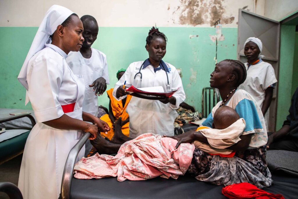 A group of healthcare workers speaking with a mom holding her baby