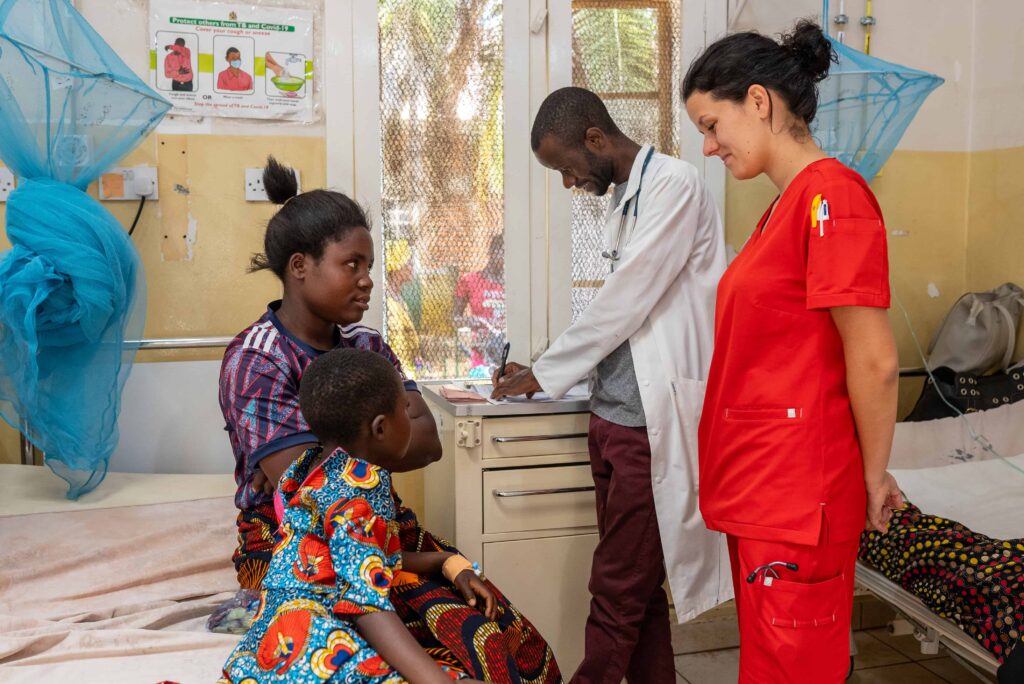 A nurse smiling and speaking with a young mom and her son