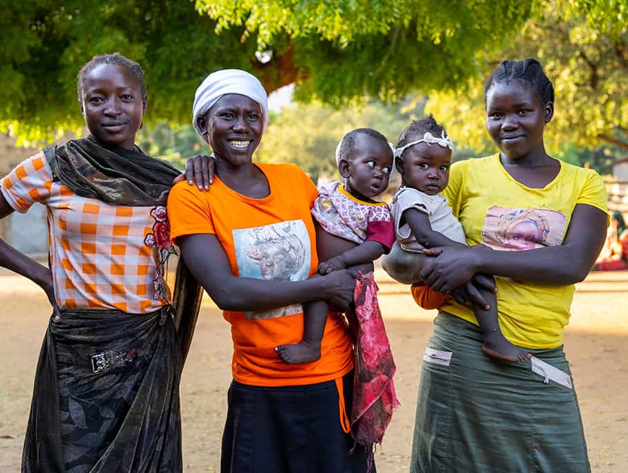 Image of women in the community, holding babies.