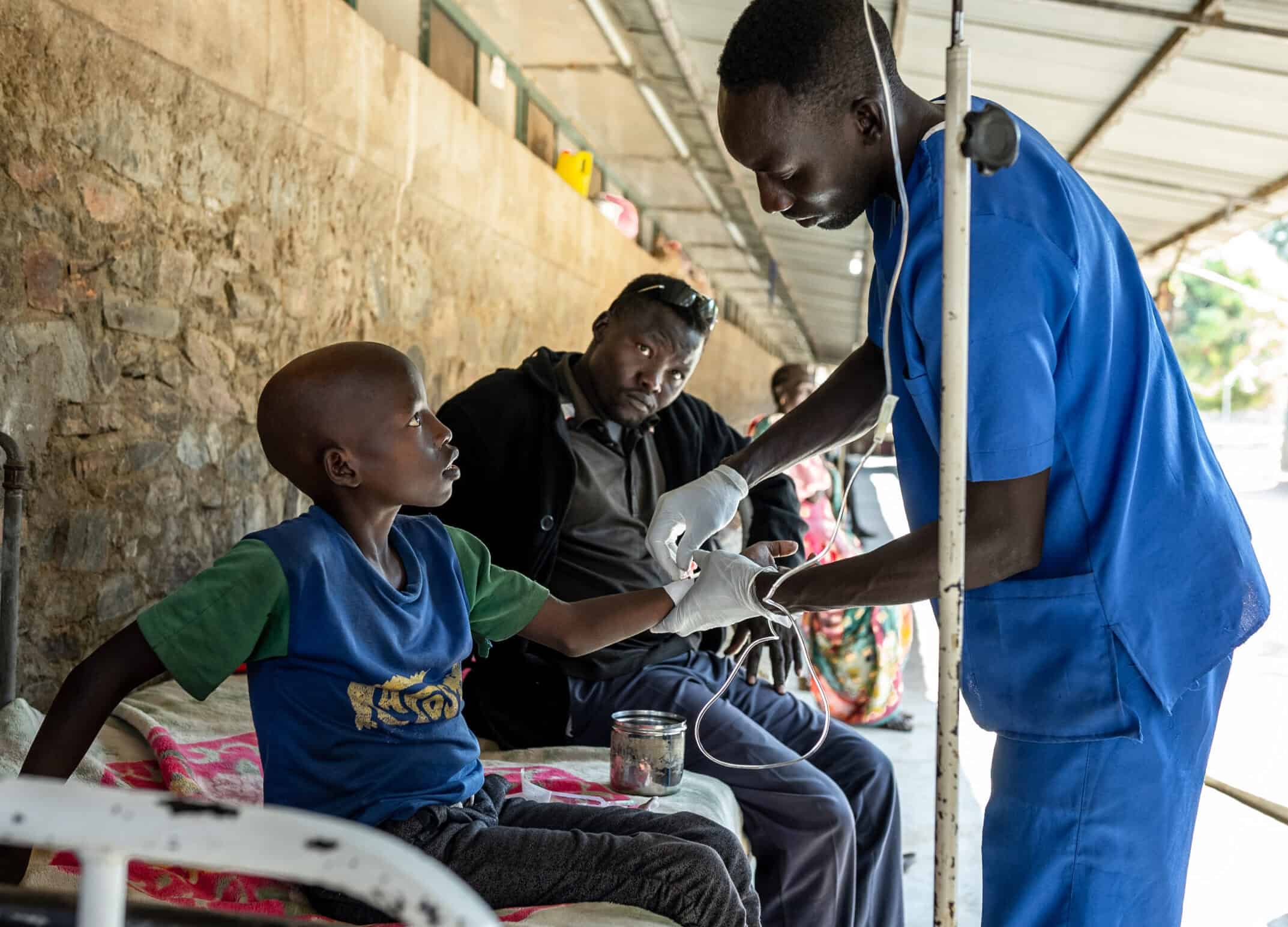 A doctor puts an IV into a young boy