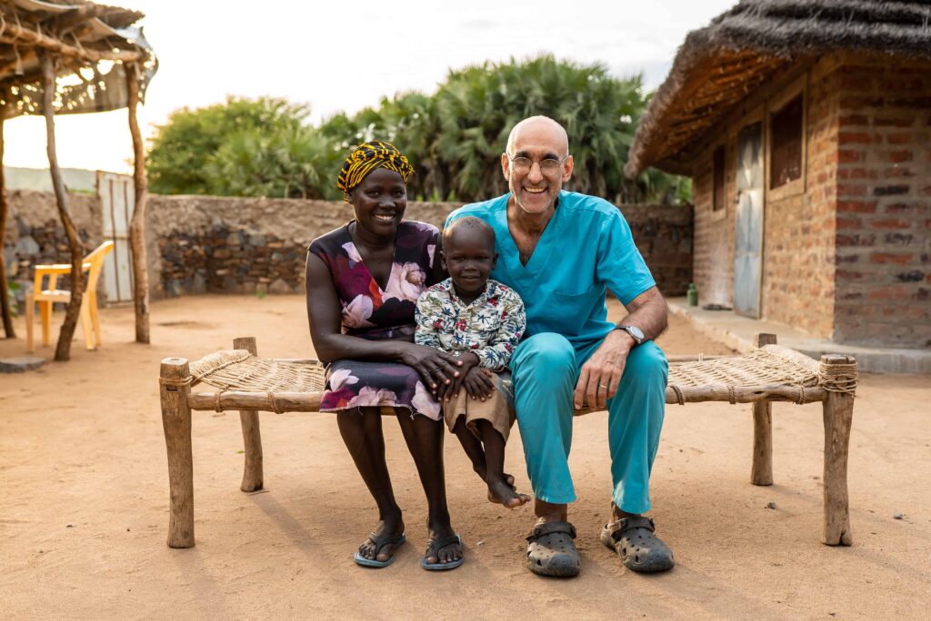 Dr. Catena sitting with a young boy and his mother outside