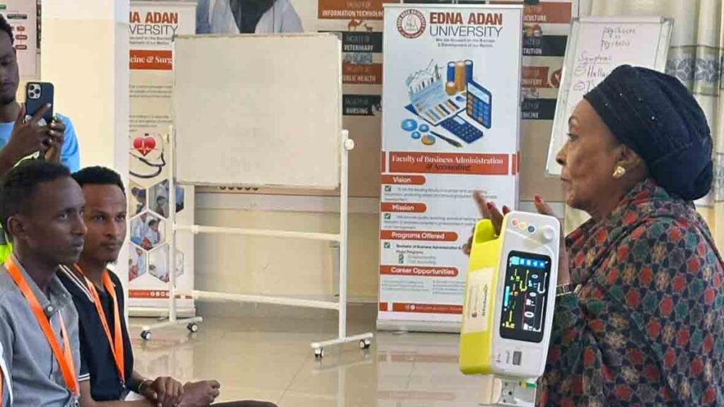 Presenter holds a monitoring device while seated participants watch a capnography demonstration.