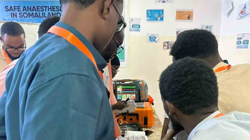 Participants gather around a training mannequin and monitoring equipment during a practical skills session.