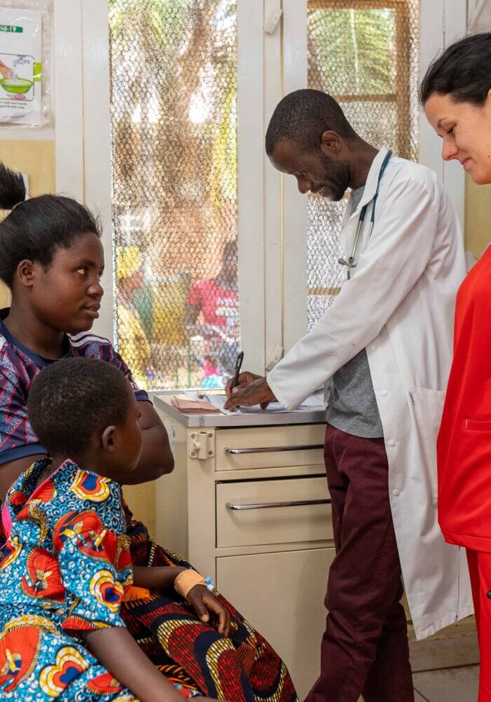 A nurse smiling and speaking with a young mom and her son