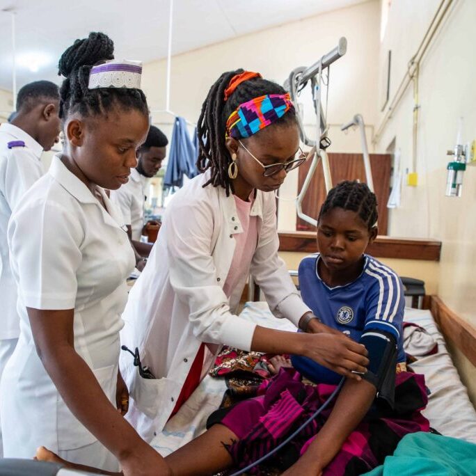 Two healthcare workers take a boy's blood pressure