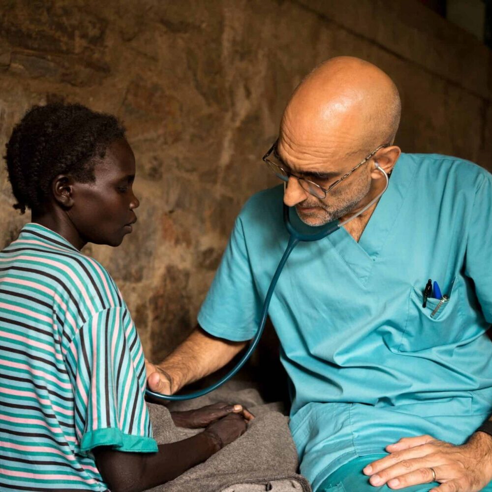 Dr. Tom Catena using stethoscope on child.