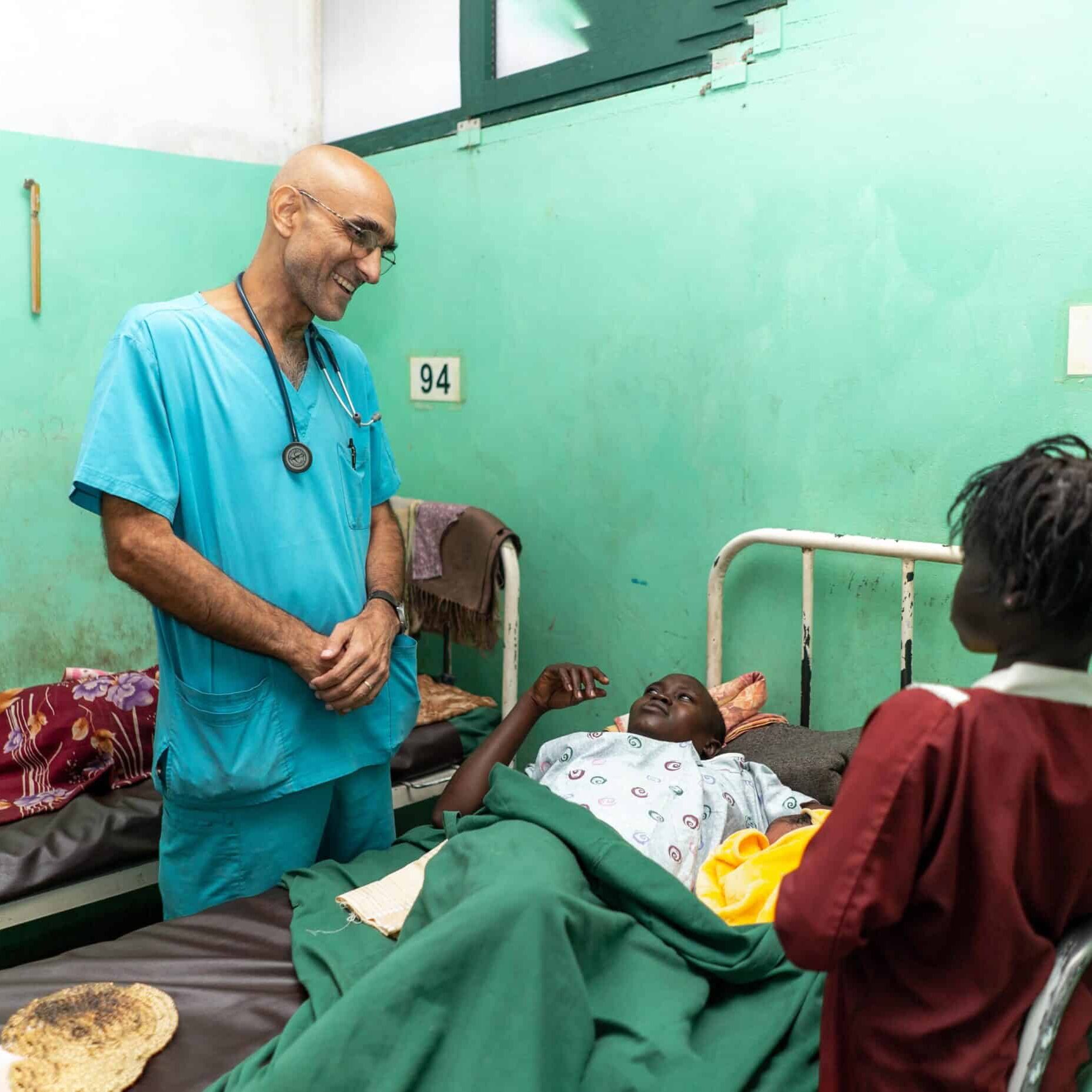 Dr. Catena smiling, talking with a young patient and his mother.